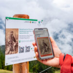 Besucher hält die App zur Biosphären-Drehscheibe am Hirschkaser vor ein entsprechendes Informationsschild