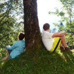 Teilnehmer einer Schulung zu Green Care lehnen meditierend an einem Baum