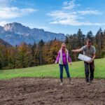 Landwirte säen mit der Hand Samenkörner des Berchtesgadener Vogel vor Gebrigskulisse