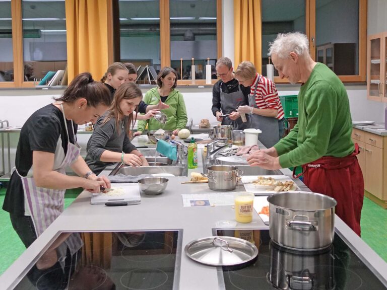 Teilnehmende eines Kochkurses bereiten ein nachhaltiges Menü zu