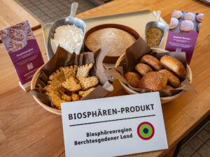 Zertifizierte Biosphären-Produkte Bergsteigerglück und Hoamat Weckerl in Körbchen präsentiert auf einem Tisch mit Biosphären-Produkt-Schild