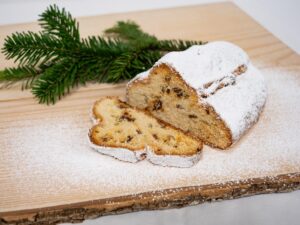 Angeschnittener Biosphären-Stollen mit Puderzucker auf einem Holzbrett