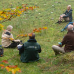 Teilnehmer einer Schulung zu Green Care sitzen meditierend auf einer Wiese