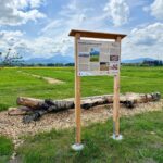 Infotafel am Biosphären-Getreidegarten mit Bergkulisse im Hintergrund
