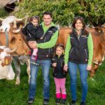 Landwirt-Familie auf einer Weide mit Kühen