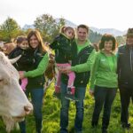 Landwirt-Familie auf einer Weide mit Kühen