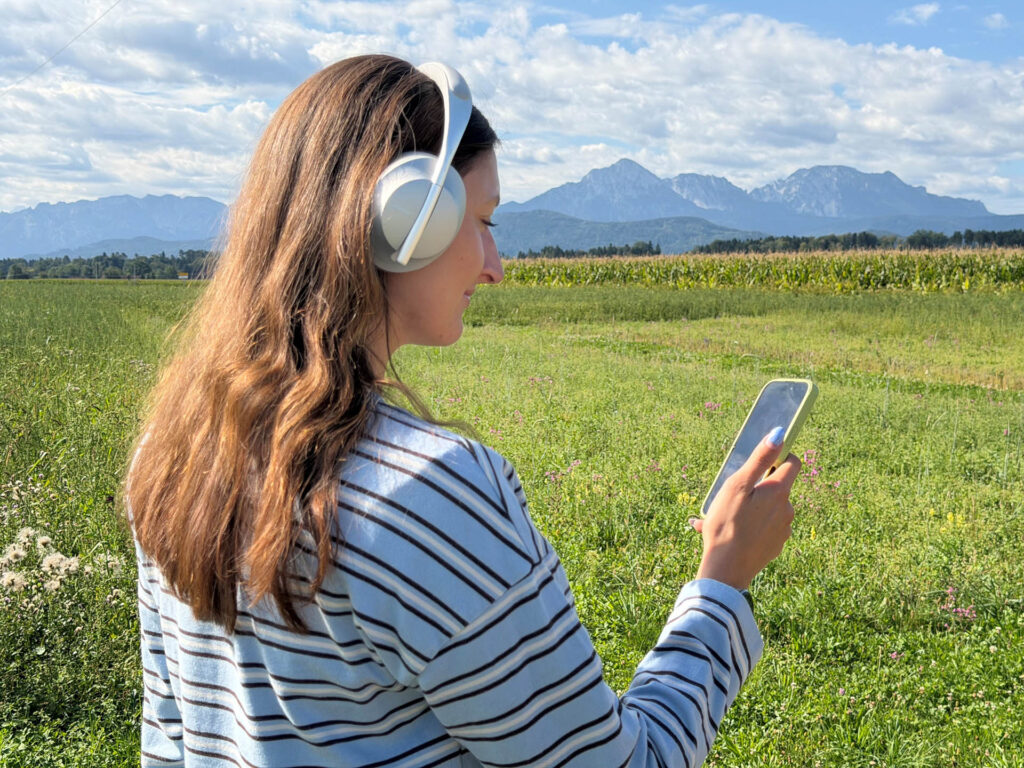Frau mit Smartphone und Kopfhörer beim Anhören des Audioguides zum Schatzbewahrer-Rundweg