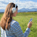 Frau mit Smartphone und Kopfhörer beim Anhören des Audioguides zum Schatzbewahrer-Rundweg